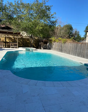 Pool with white travertine deck and spa